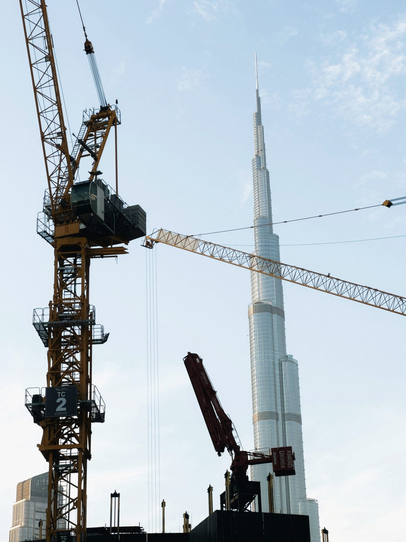 A MONO development under construction — tower crane on site, Burj Khalifa beyond